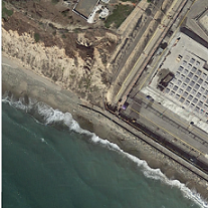 Birds eye view of a beach with ocean waves and a lot of buildings on the coast