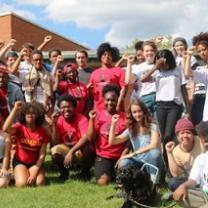 Young people posing outside wearing mostly red shirts with their fists in the air