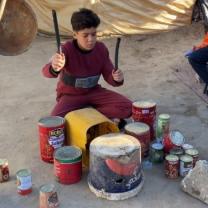 Young boy playing on homemade drums