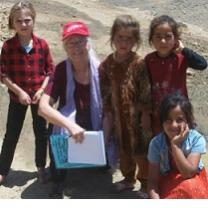 Older gray haired white woman posing outside with four dark skinned young girls