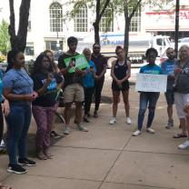 Students standing outside holding signs on a city street