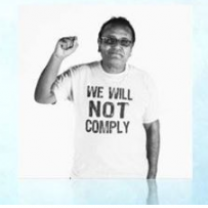 Latino man holding up a fist with a t-shirt saying we will not comply