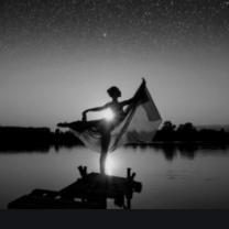 Silhouetted figure of woman posing near a lake and horizon 