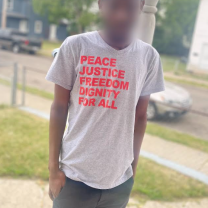 Man in T-shirt saying Peace, Justice, Freedom, Dignity for all