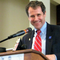 Middle aged white man at a podium smiling