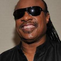 Smiling black man with big sunglasses and long braids in a black shirt