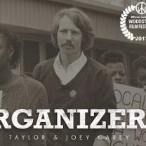 Black and white photo of a man with long hair and a moustache and the word ORGANIZER