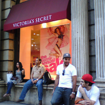 People sitting on a ledge outside a Victoria's Secret store