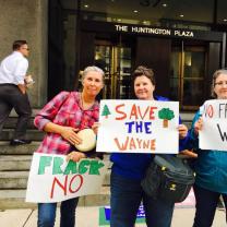 Three women holding signs about saving the Wayne National Forest
