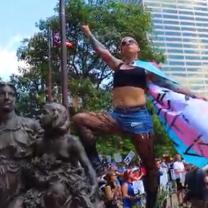 Woman posing on statue wearing trans flag