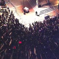 A person on a stage and the audience from a view high up above in the rafters.