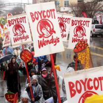 People marching in the rain with Boycott Wendy's signs