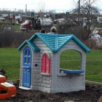 Backyard kid's playhouse with frackers working jsut behind it