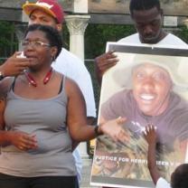 Black woman talking and pointing to photo of her son, young black man