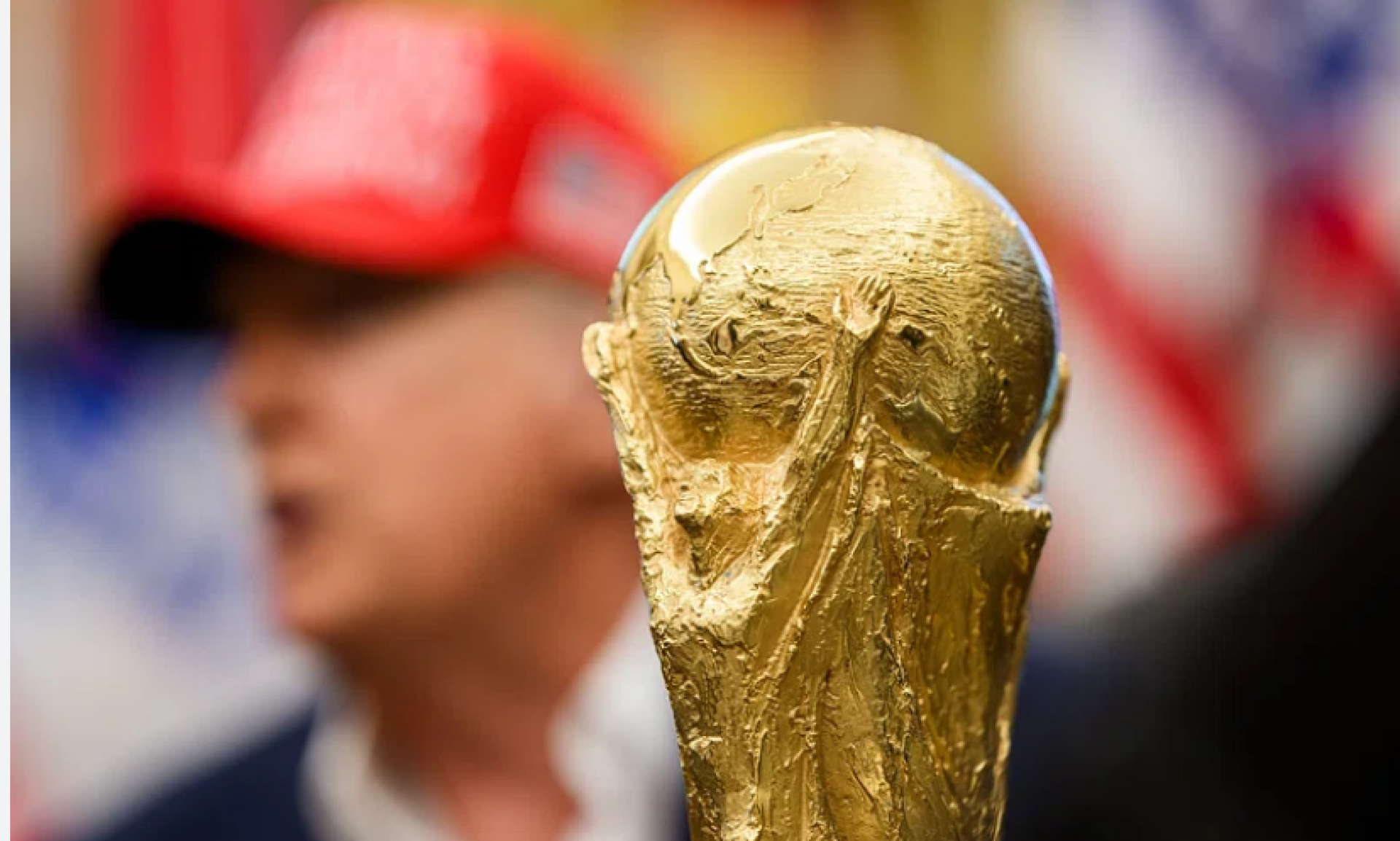 World Cup trophy with Trump blurred in the background