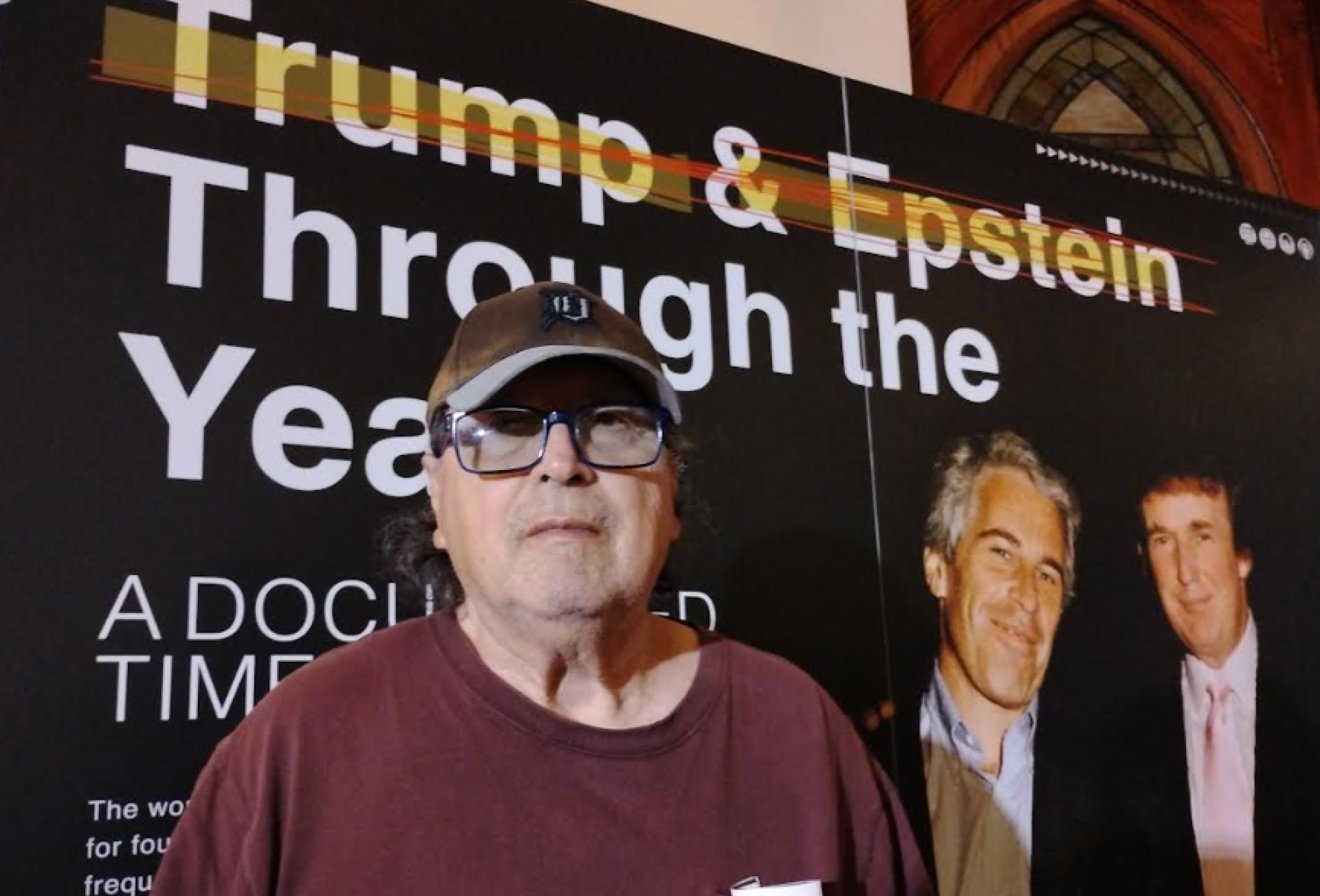 Bob by big poster of Trump and Epstein